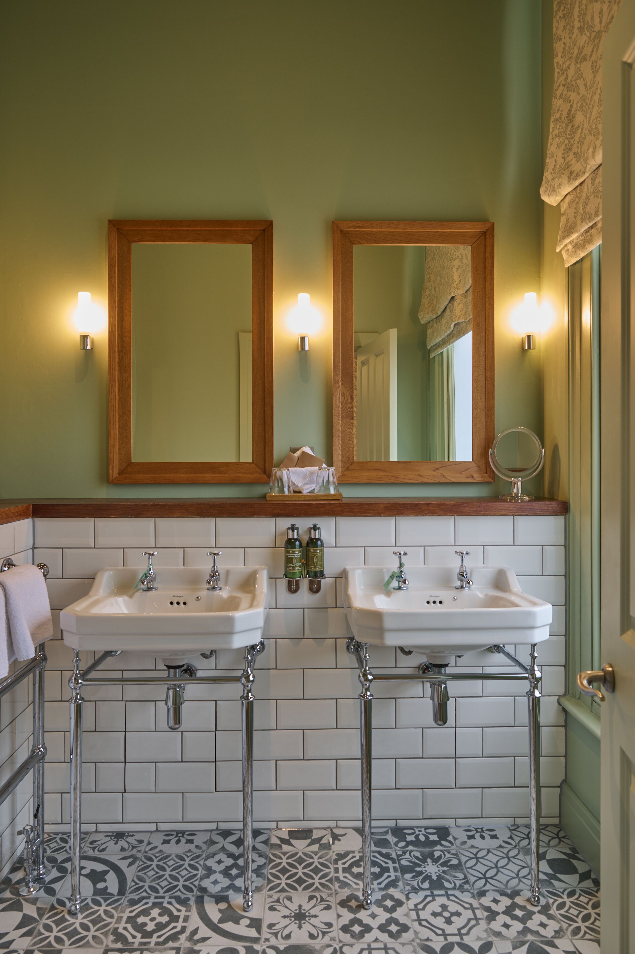Een badkamer met twee wasbakken, een spiegel en een handdoekhouder.