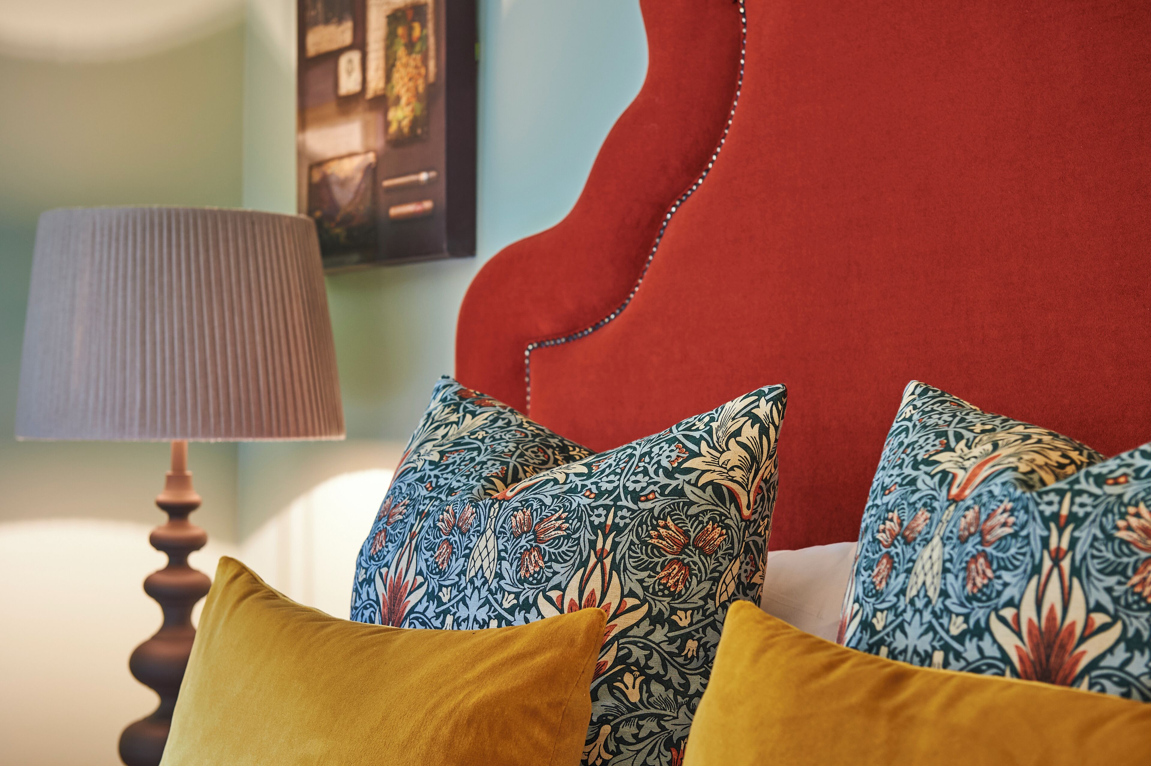 Un letto con cuscini decorati e una testiera rossa.