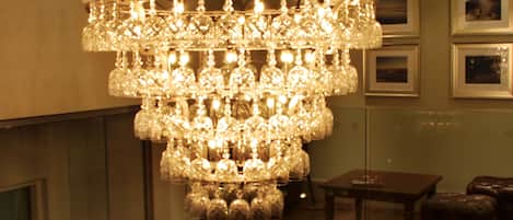 A chandelier with multiple glass bulbs hanging from a ceiling in a room with wooden furniture and framed pictures on the wall.