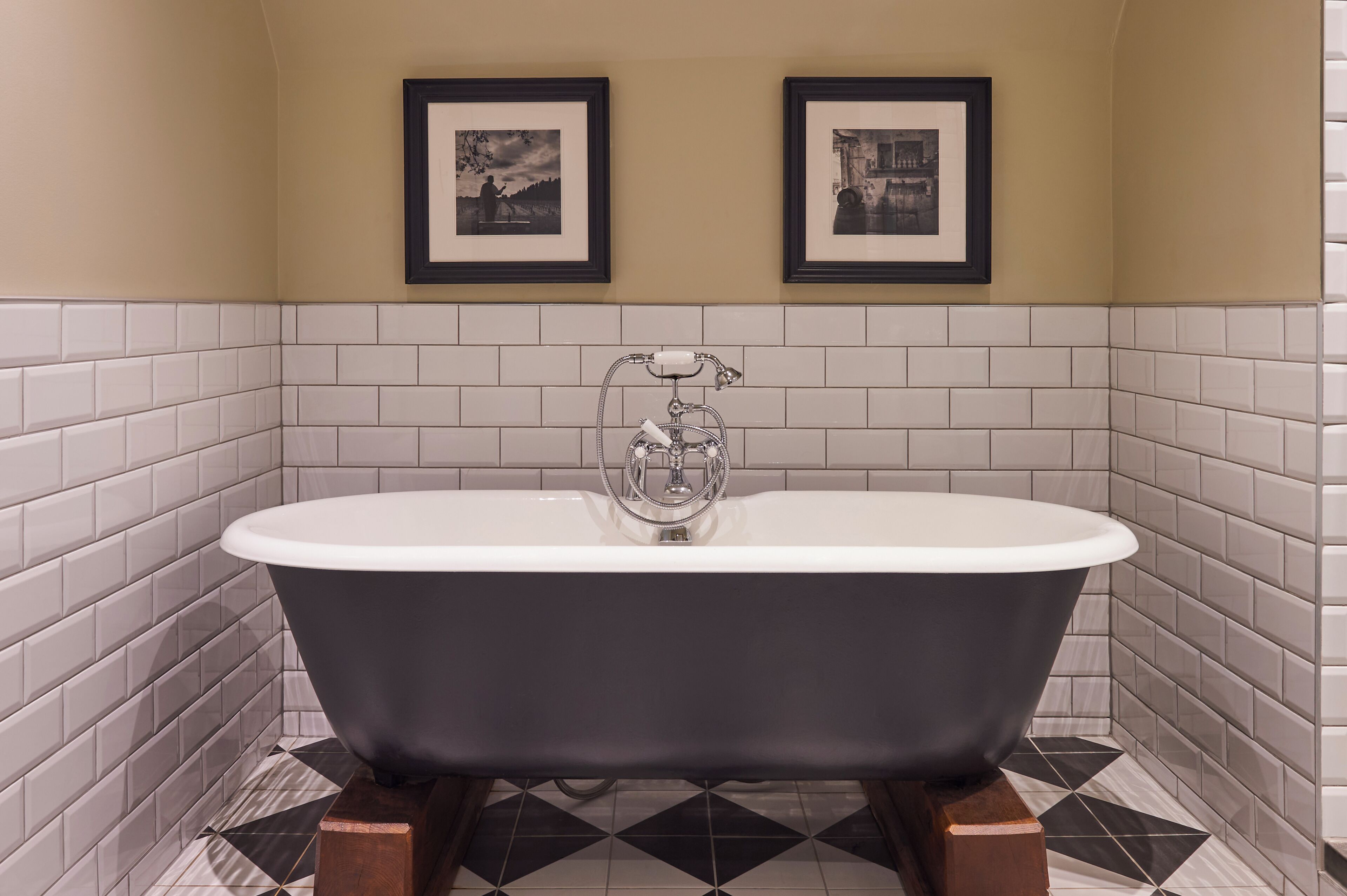A bathroom with a freestanding bathtub, white tiled walls, and a patterned floor.