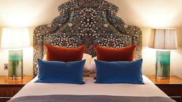 A bed with a patterned headboard, two blue pillows, and two red pillows.