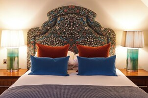 A bed with a patterned headboard, two blue pillows, and two red pillows.