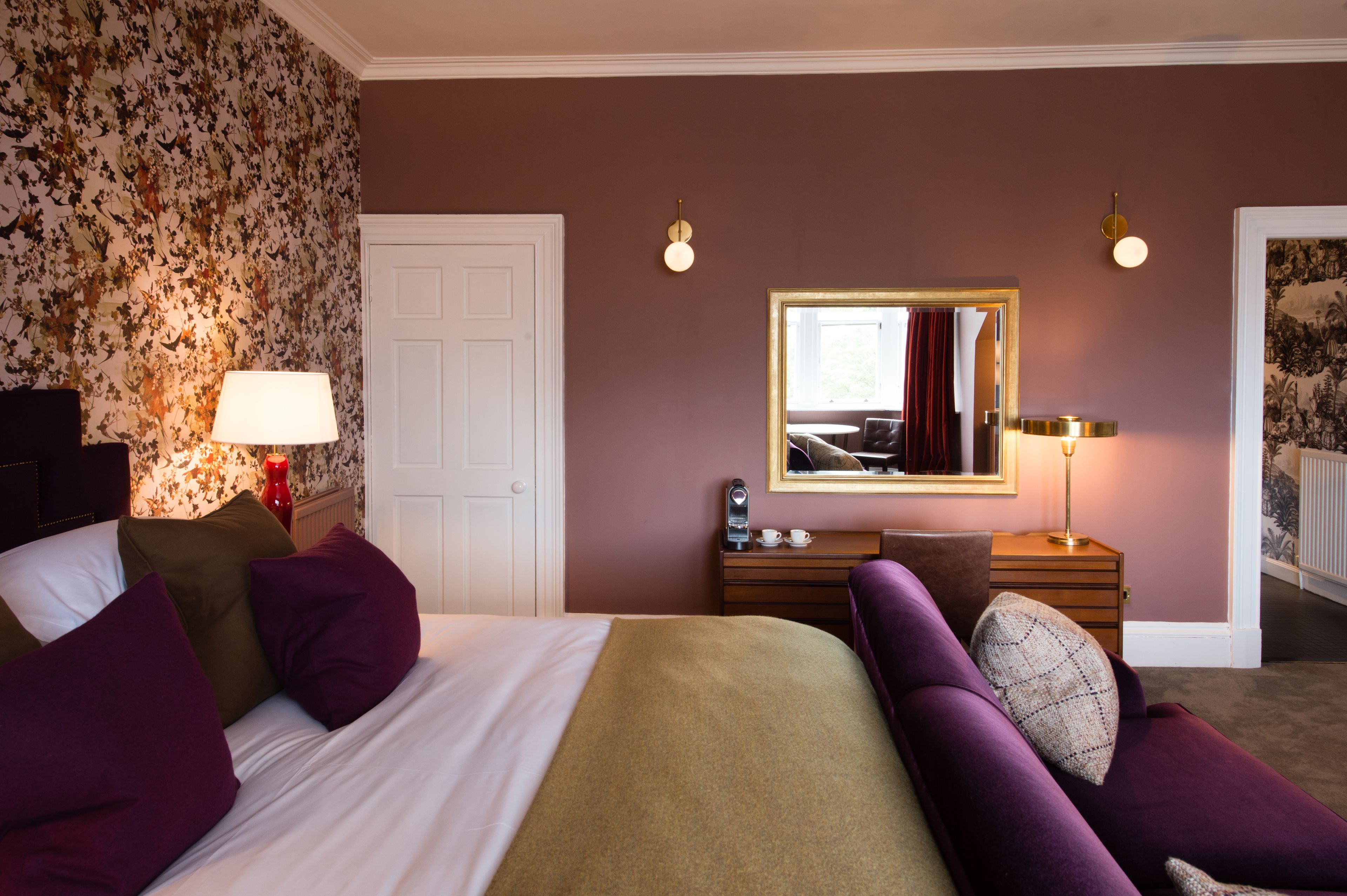 Una habitación de hotel con una cama, un tocador, un espejo y una lámpara.