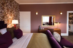Una habitación de hotel con una cama, un tocador, un espejo y una lámpara.