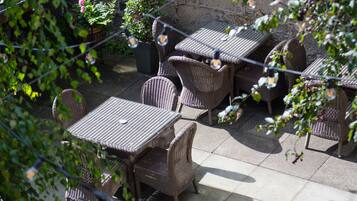 An outdoor patio with wicker furniture and string lights.