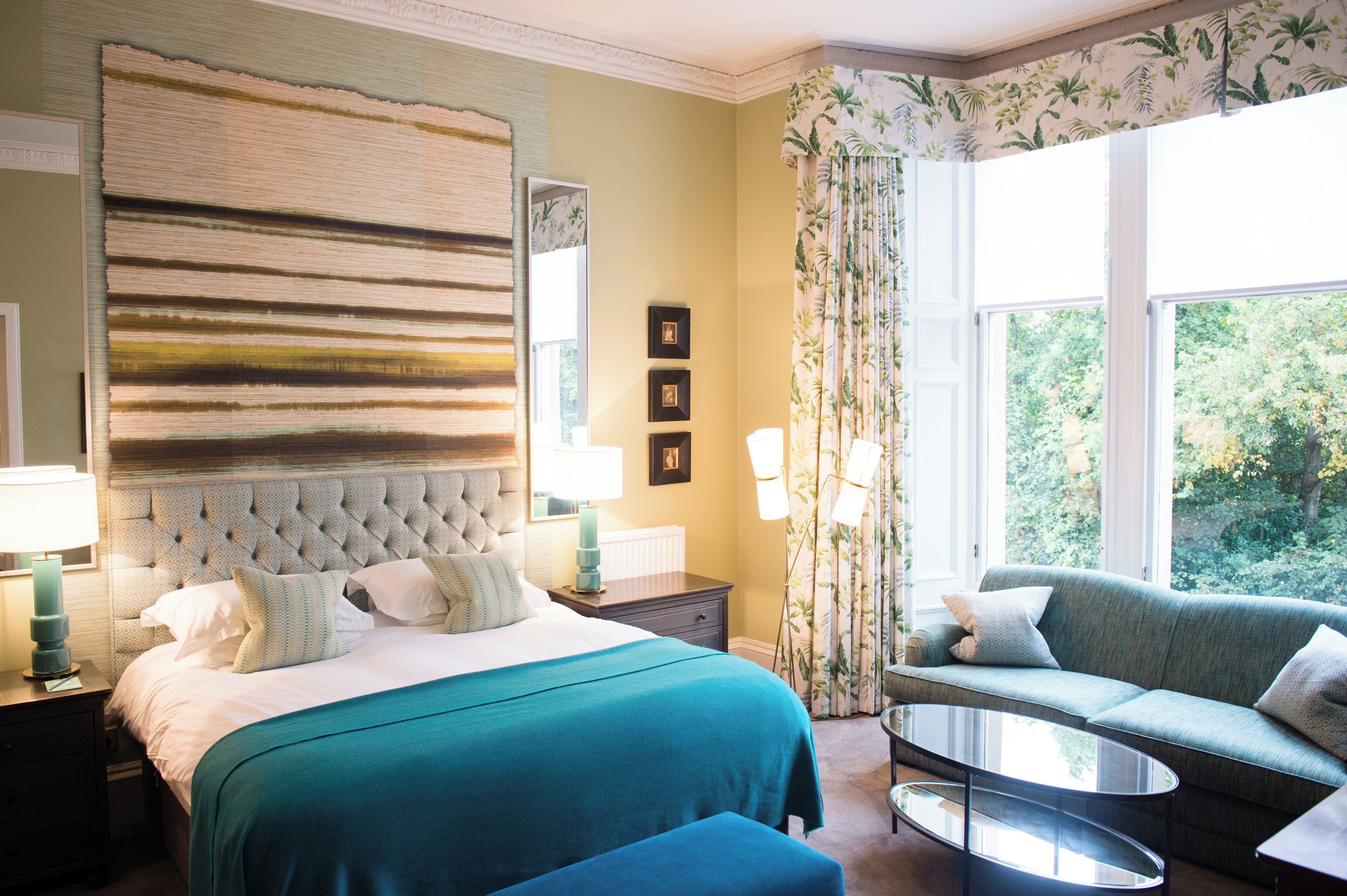 Habitación de hotel con una cama grande, un sofá, una mesa de centro y vistas al exterior.
