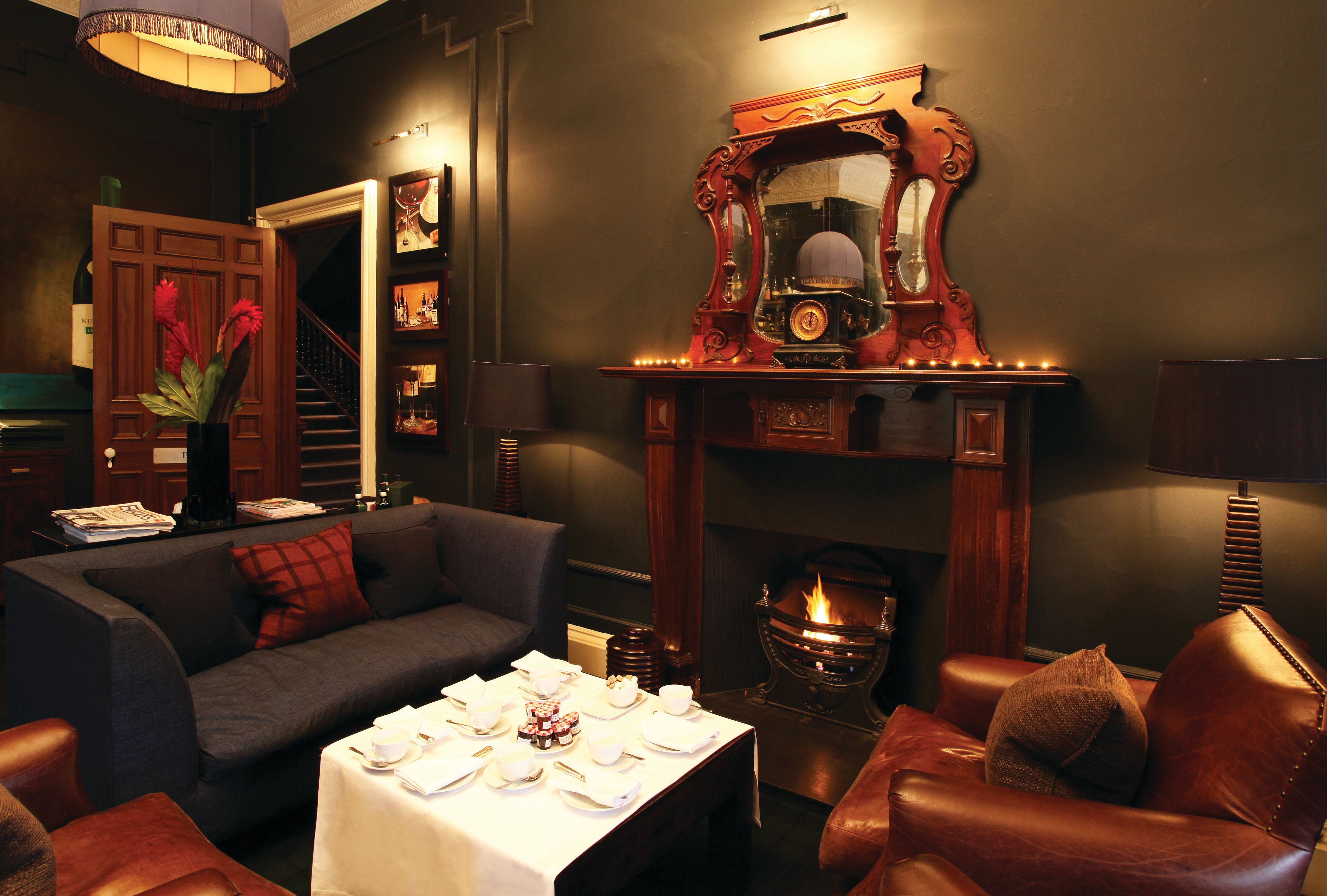 Una sala de estar acogedora con chimenea, un sofá, una mesa lista para comer y un espejo decorativo.