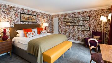 Een slaapkamer met een bed, nachtkastjes, een bankje, een stoel, een tafel en wanddecoratie.