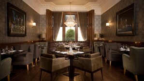 Uma sala de jantar formal com uma mesa grande, várias cadeiras e um candelabro.