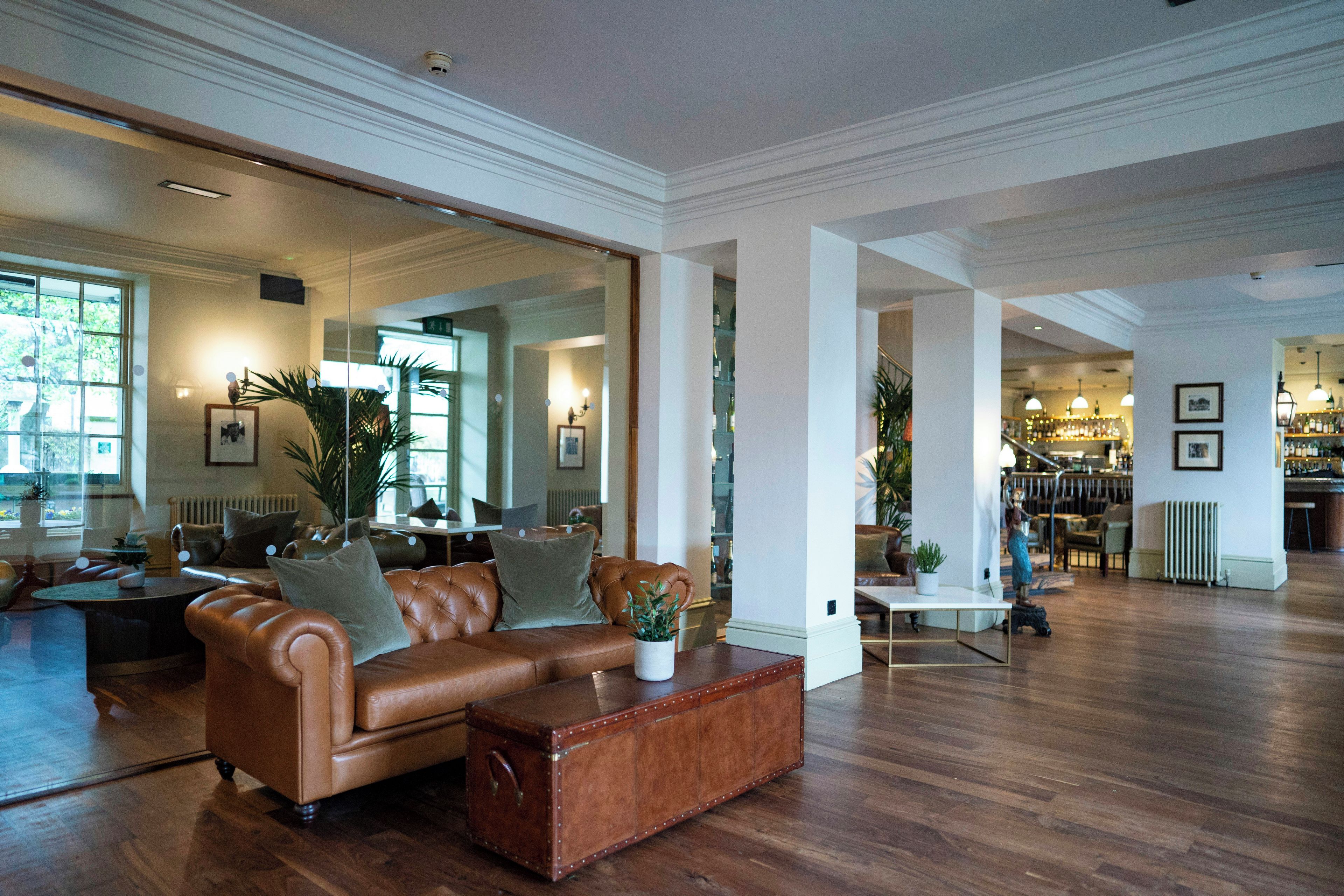 A spacious living area with a leather sofa, a coffee table, and a large mirror reflecting the room.