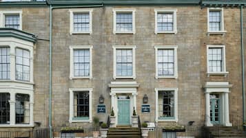 A historic building with a symmetrical facade, multiple windows, and a central entrance with a green door.