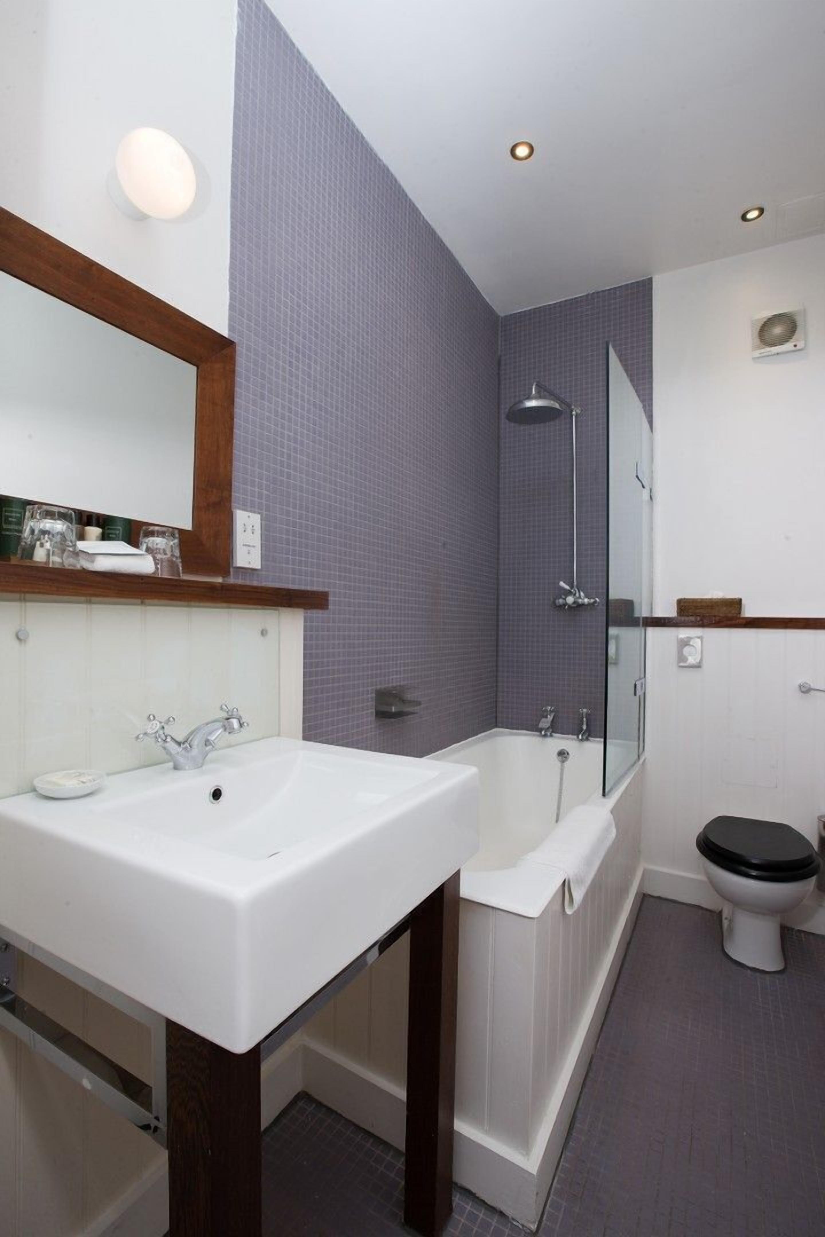 A modern bathroom with a large sink, a bathtub, and a toilet.