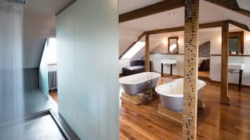 A modern bathroom with a freestanding bathtub, a large mirror, and wooden beams.