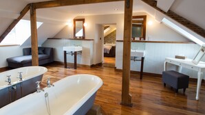 Un dormitorio en el ático amplio, con una bañera grande, dos lavamanos y una zona de estar acogedora.