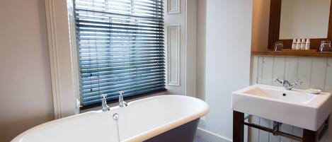 A bathroom with a freestanding bathtub, a sink, and a mirror.