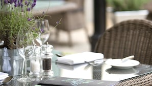 Una mesa de comedor dispuesta con cristalería, un menú y una maceta con lavanda.