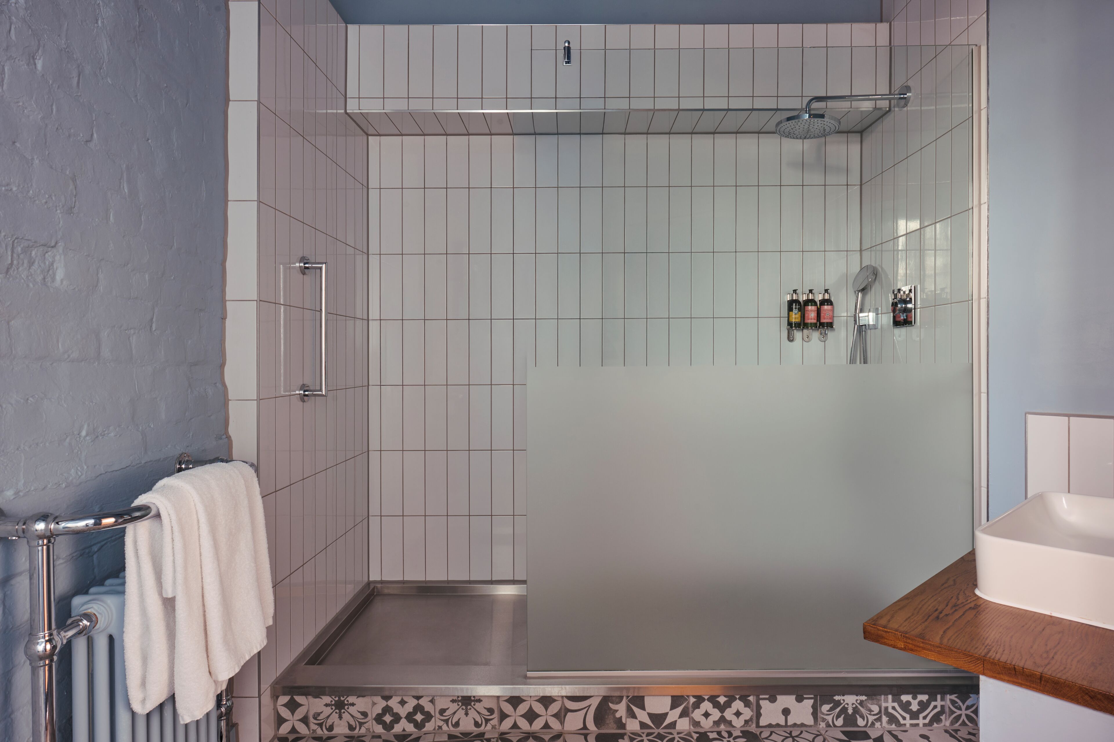 A modern bathroom with a glass shower enclosure, a white sink, and a towel rack.