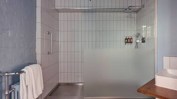 A modern bathroom with a glass shower enclosure, a white sink, and a towel rack.