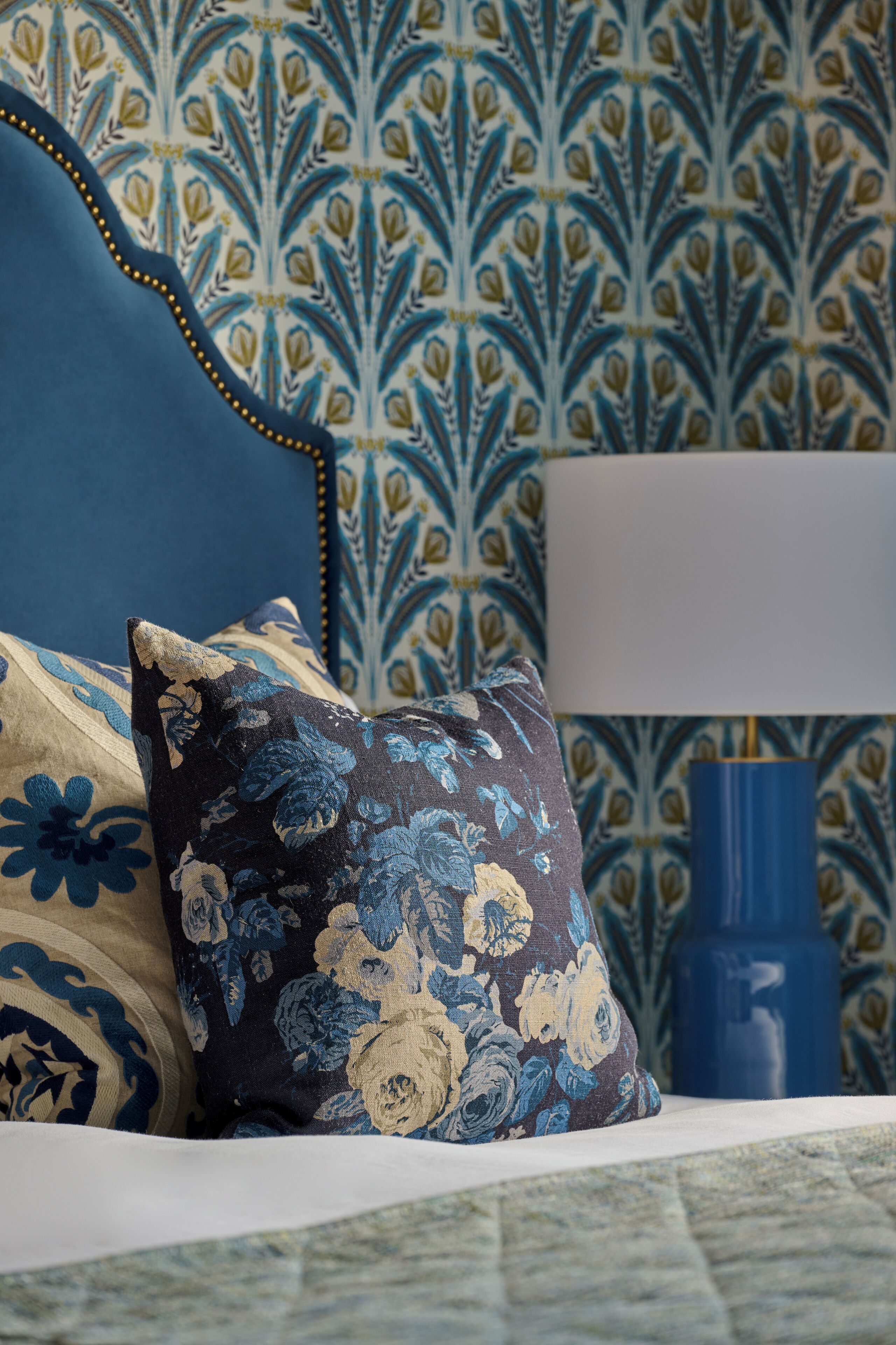 A bed with floral-patterned pillows and a blue headboard.