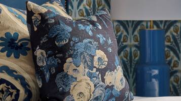 A bed with floral-patterned pillows and a blue headboard.