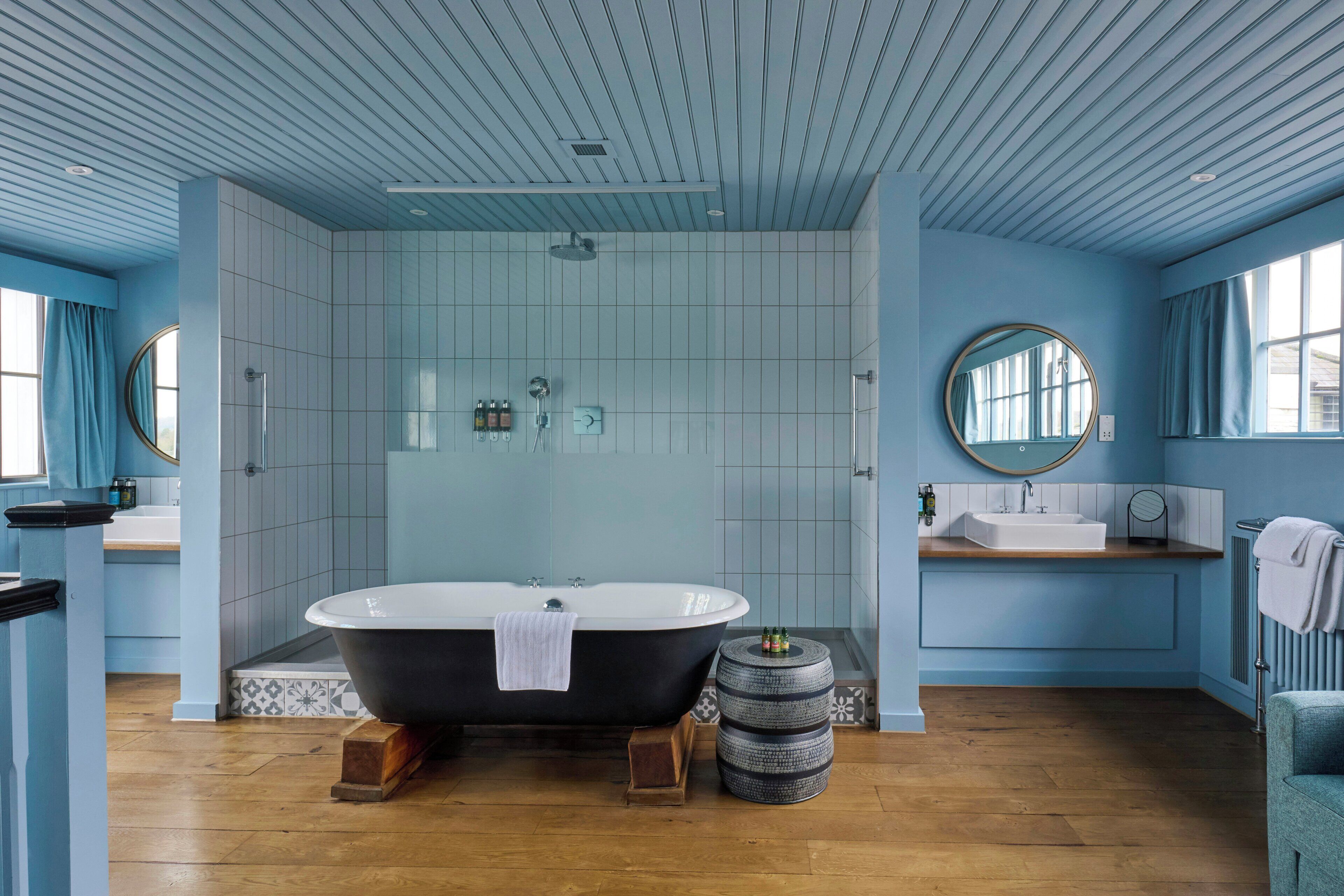 A modern bathroom with a freestanding bathtub, a round mirror, and a sink.