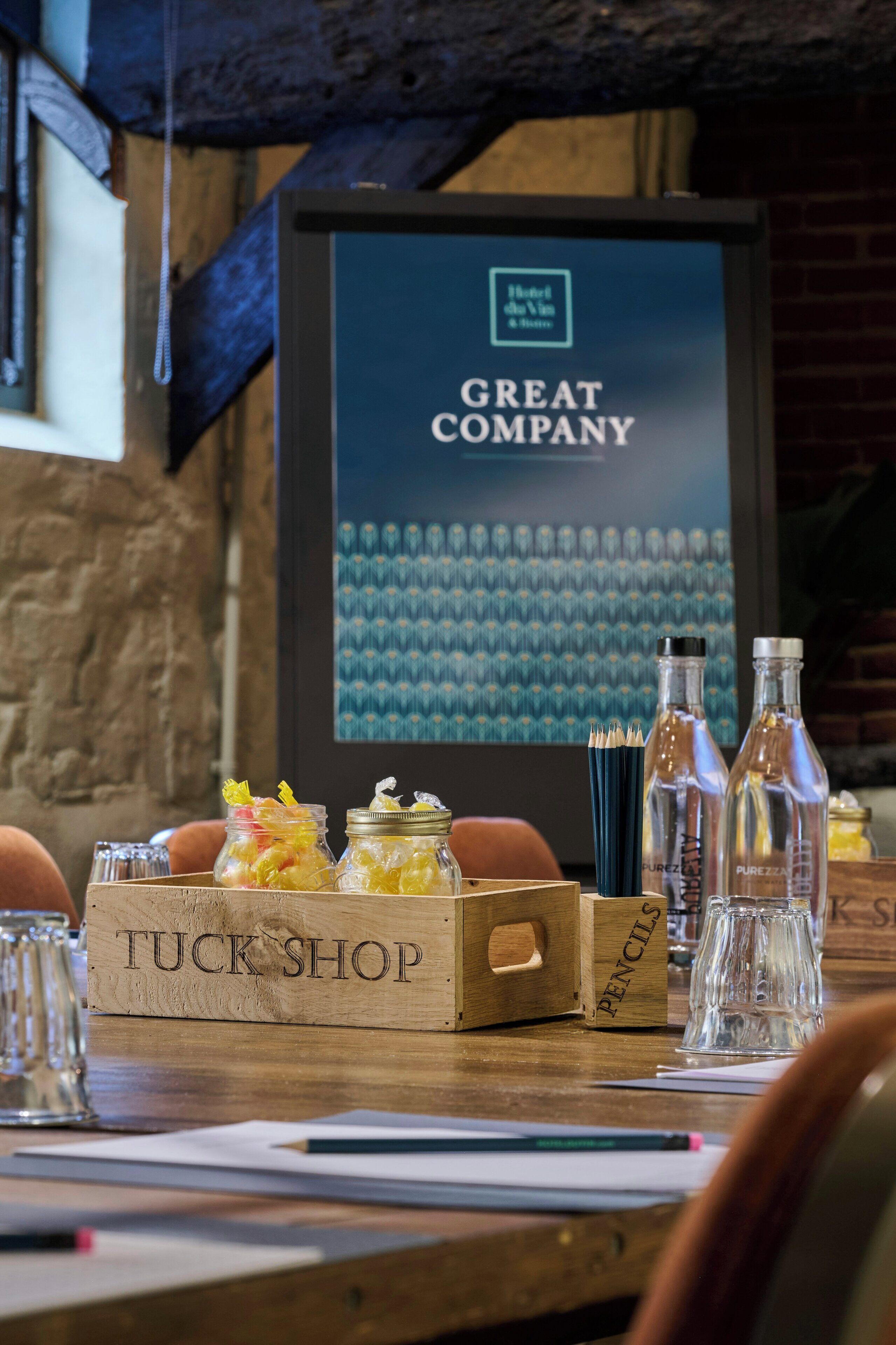 Una mesa de madera con un letrero que dice "TUCK SHOP" y un cartel enmarcado al fondo.