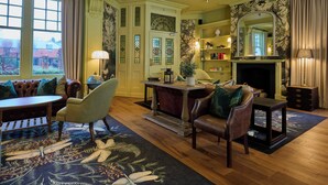 A traditional room with a fireplace, leather furniture, and a view of a garden through large windows.