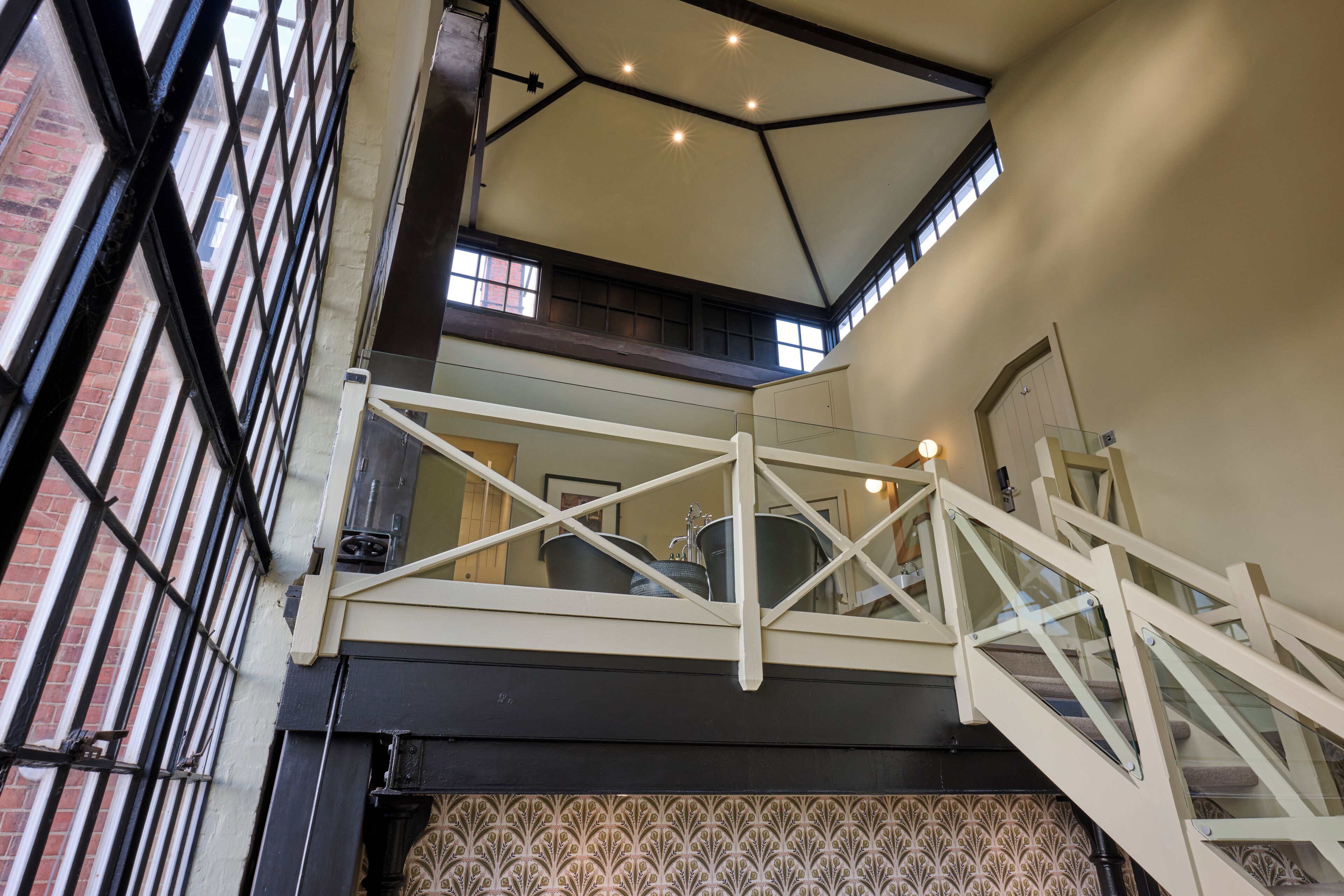 A multi-level interior with a staircase, a patterned wall, and a view of the outside through a window.
