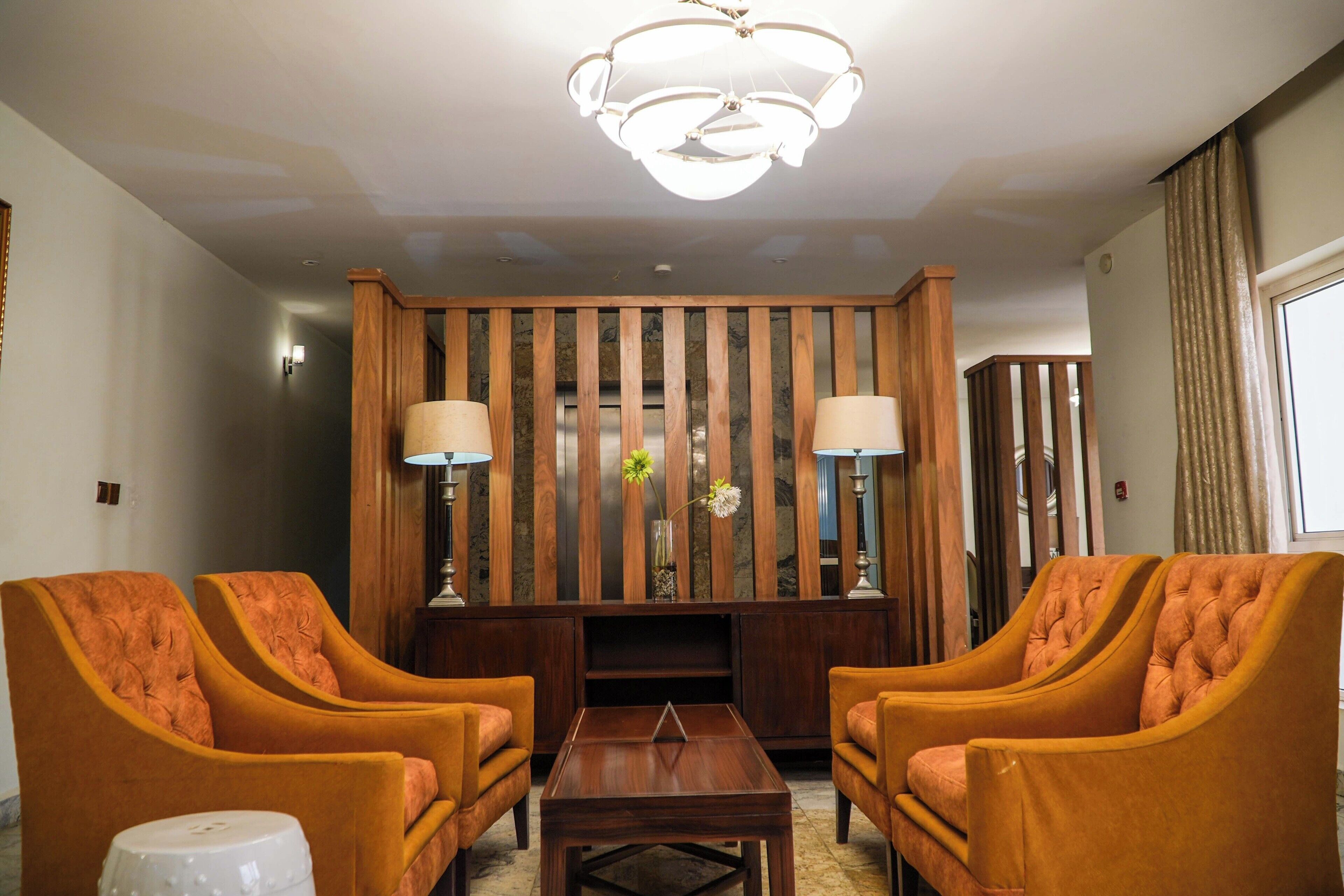 A room with two orange armchairs, a wooden coffee table, and a decorative panel with vertical slats.
