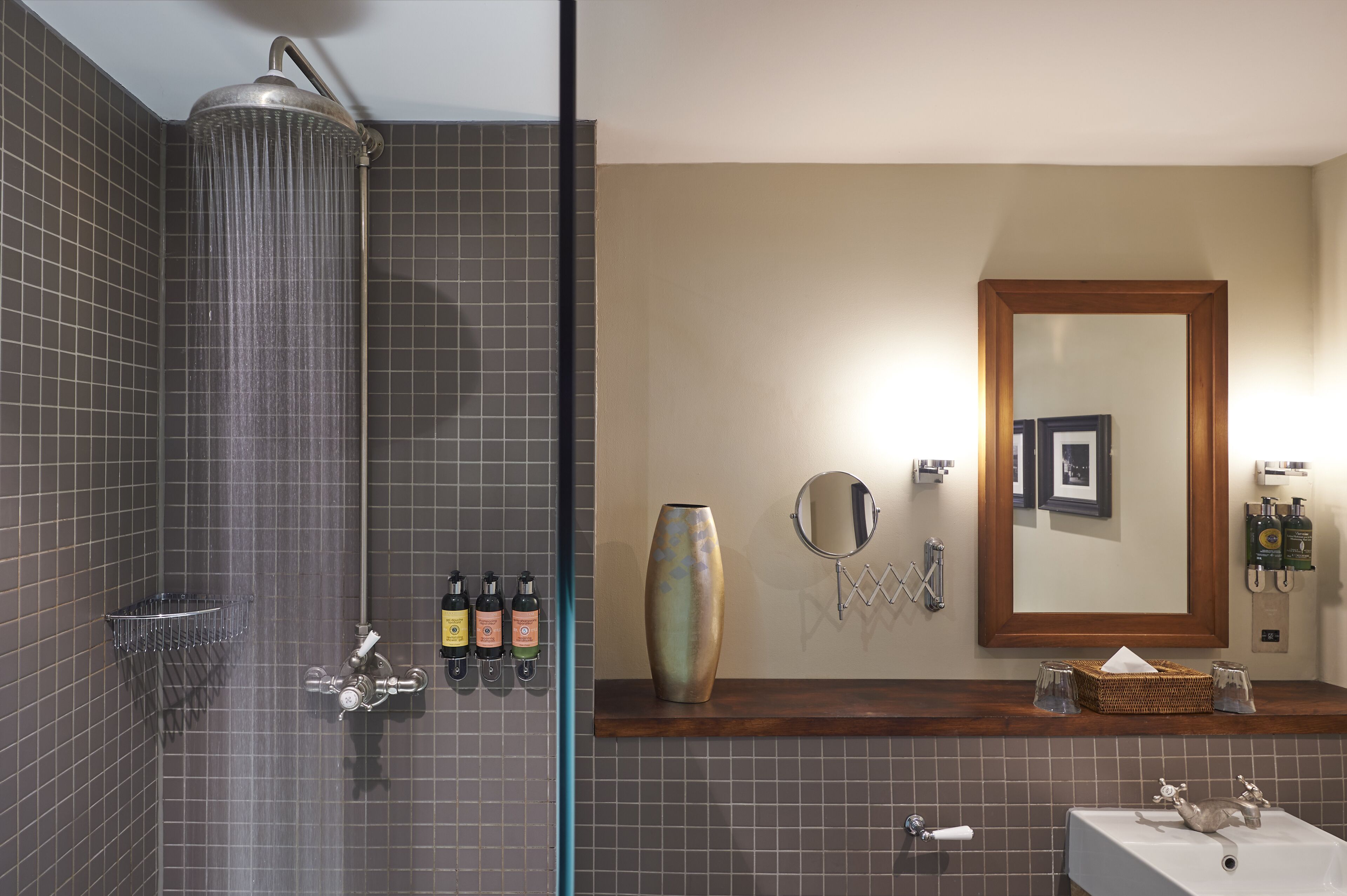 Ein Badezimmer mit Dusche, Waschbecken, Spiegel und Pflegeprodukten.