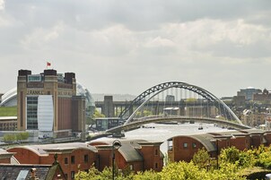 Un paisaje urbano con un puente destacado, un estadio y un río.