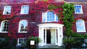 A red brick building with white-framed windows, a central entrance with a white door, and a black wrought iron fence. - Hotel du Vin & Bistro Poole (Poole)