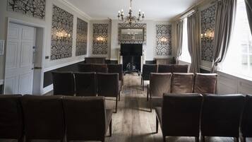 A formal dining room with a fireplace, patterned walls, and a chandelier.