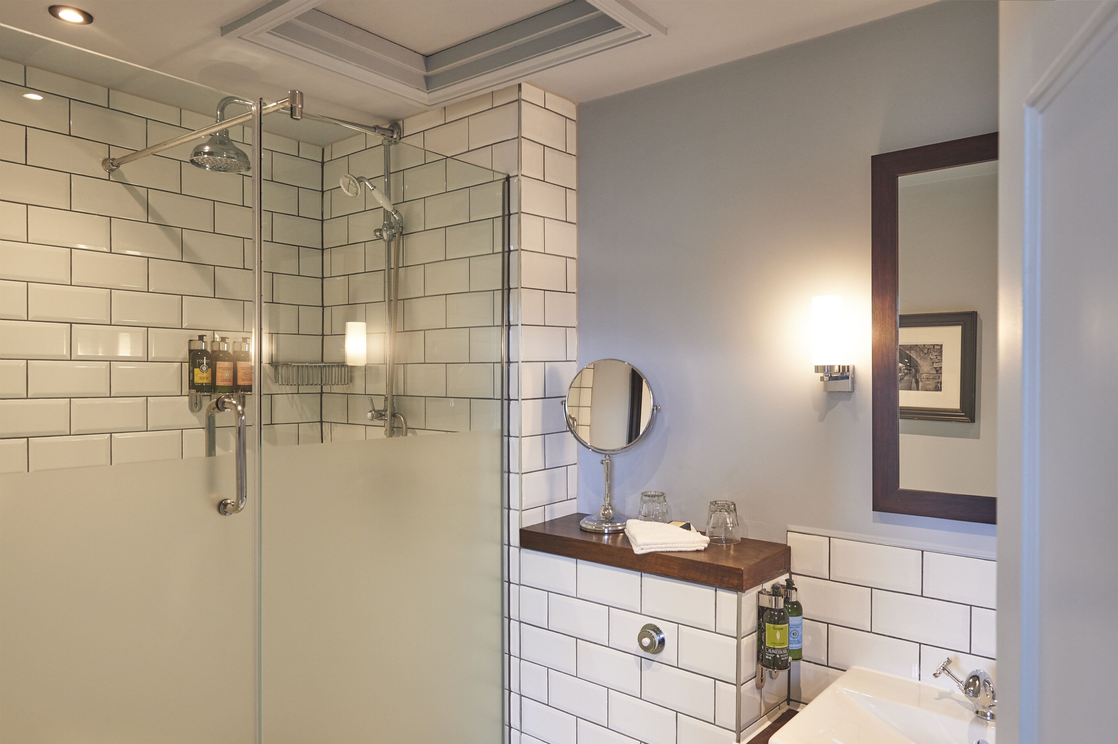 Une salle de bain moderne avec une douche à parois de verre, un lavabo avec un miroir et des articles de toilette posés sur le comptoir.