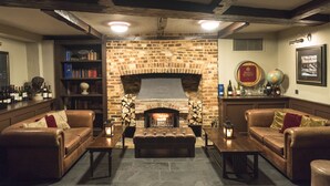 A cozy living room with a brick fireplace, leather sofas, and a bookshelf. - Hotel du Vin & Bistro Poole (Poole)