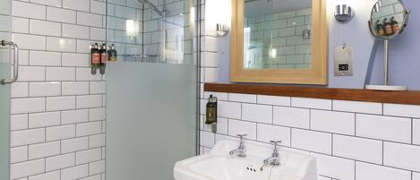 A bathroom with a glass-enclosed shower, a white sink with chrome fixtures, and a wooden-framed mirror above it.