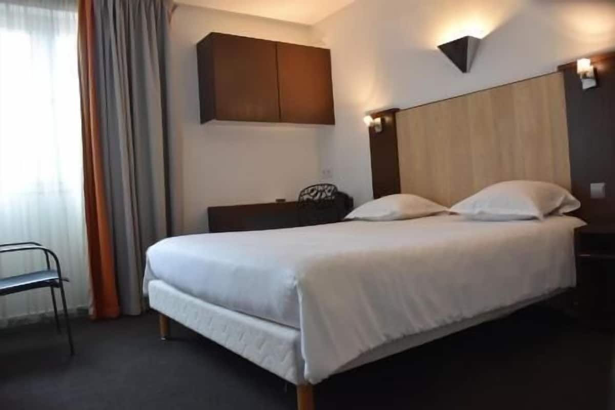 Une chambre d’hôtel comprenant un lit, une table de chevet, une chaise et une armoire.
