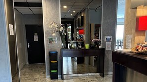 A hotel lobby with a marble floor, a reception desk, and a glass door leading to a room. - Adonis Arc Hôtel Aix (Aix-en-Provence)