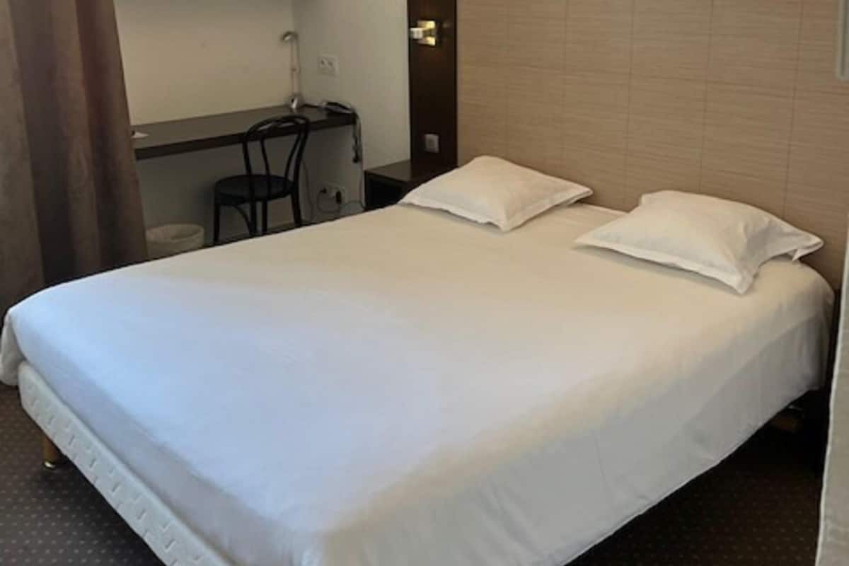 Une chambre d’hôtel avec un grand lit, un bureau et une chaise.