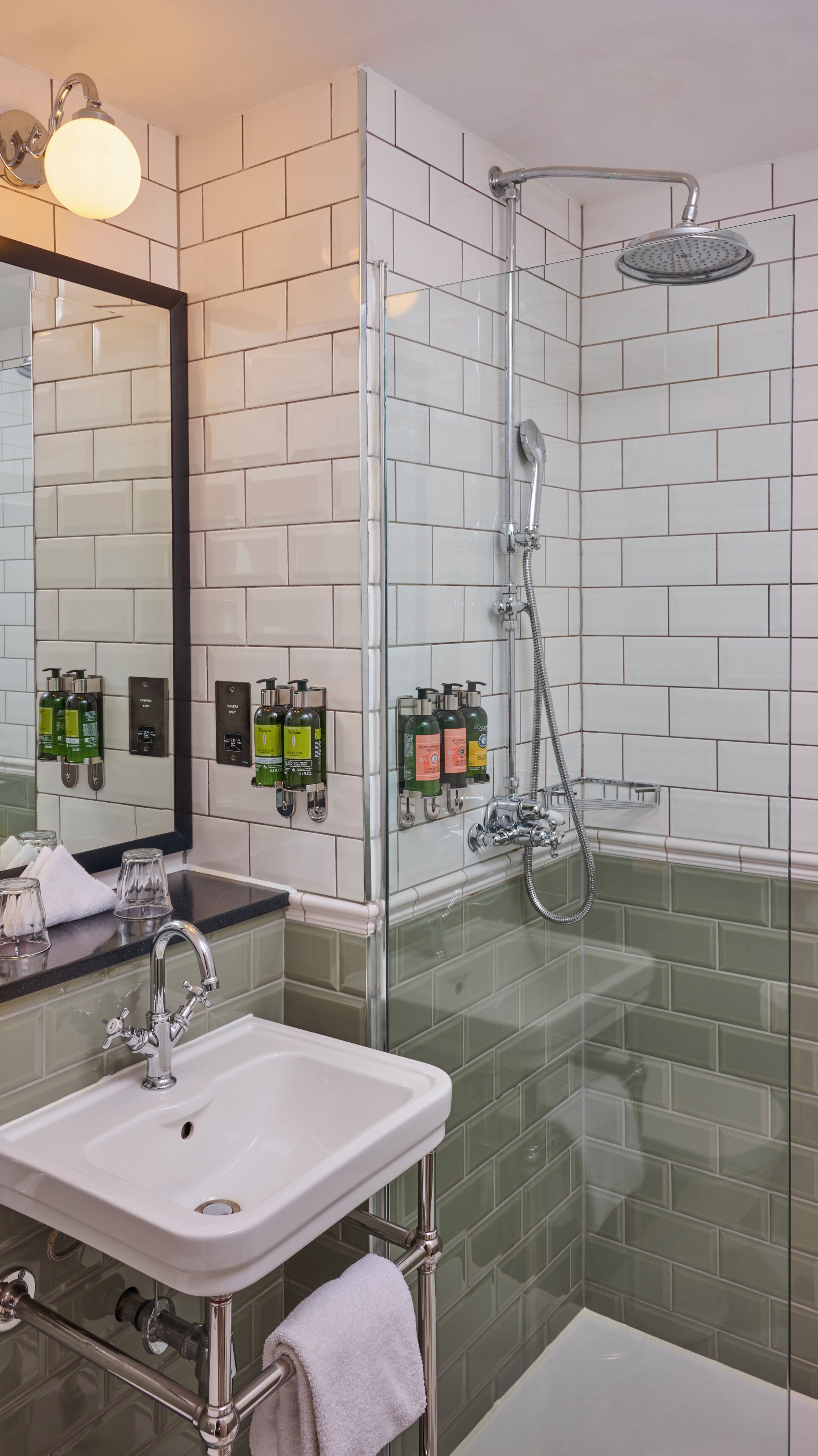 A modern bathroom with a glass-enclosed shower, a white sink, and a mirror with a black frame.