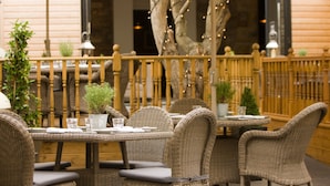 An outdoor dining area with wicker furniture, potted plants, and string lights.
