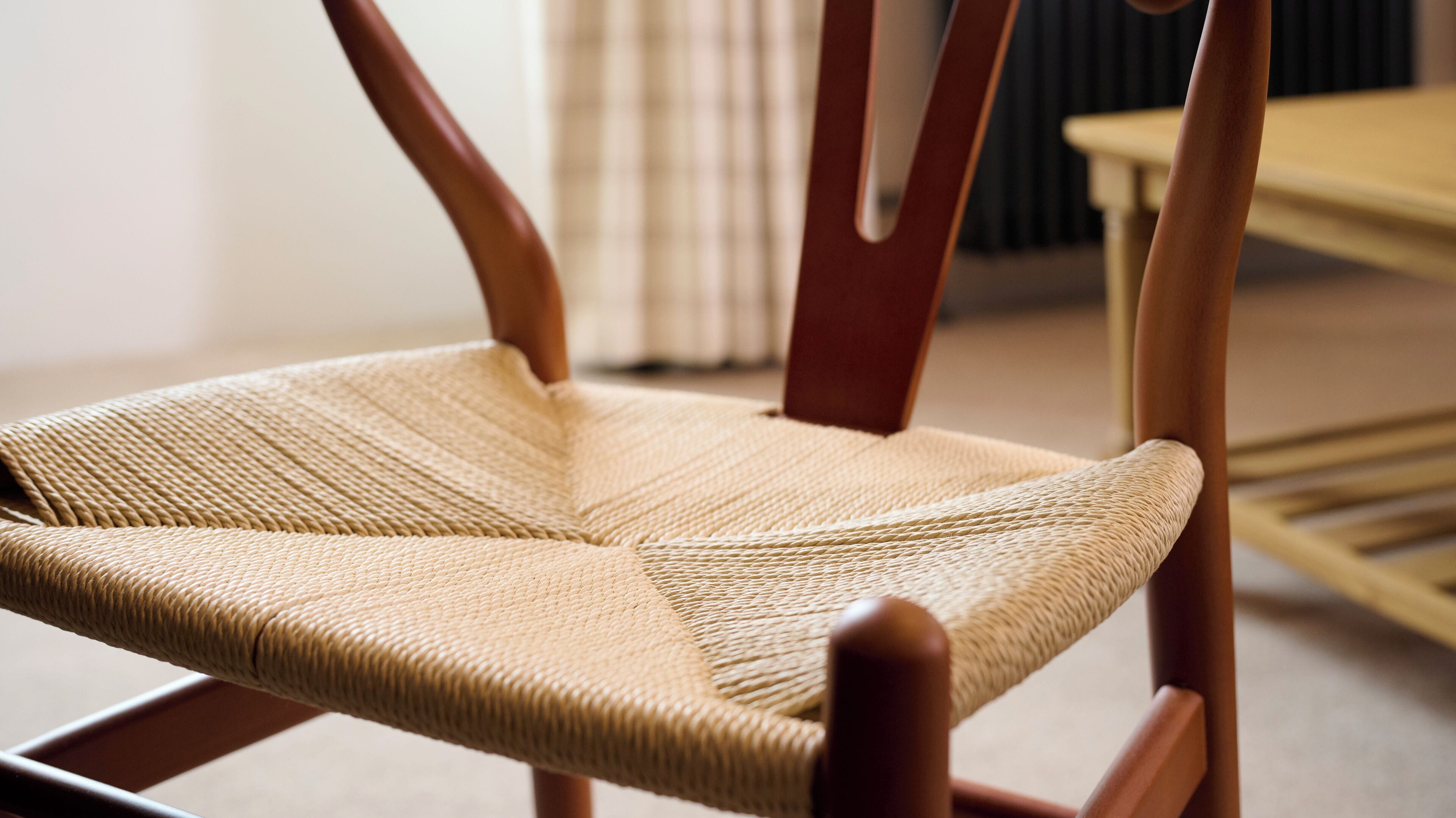A close-up of a woven chair with a wooden frame.