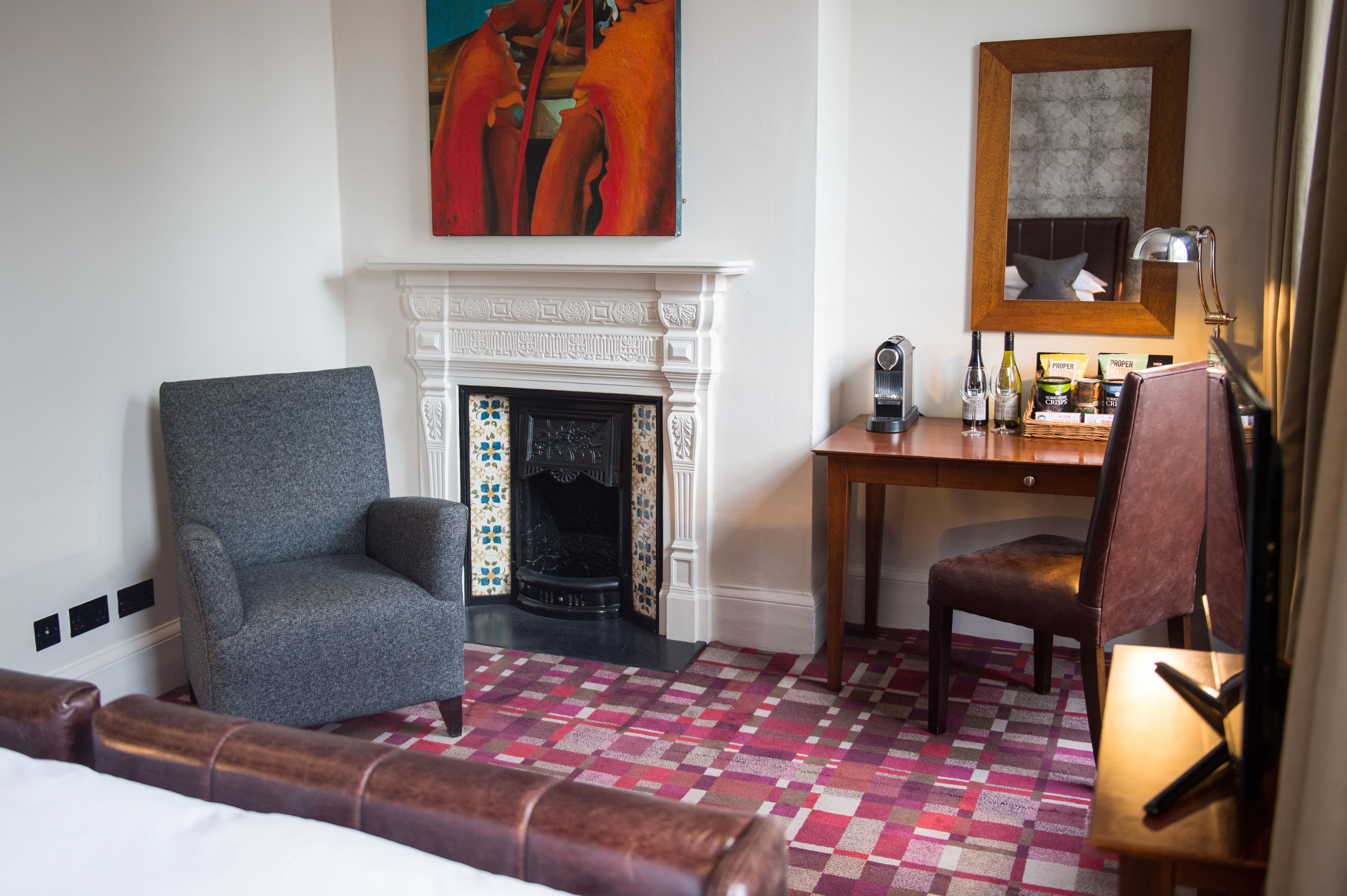 Habitación de hotel con chimenea, escritorio, una silla y una cama.