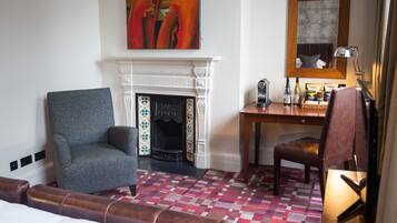 Habitación de hotel con chimenea, escritorio, una silla y una cama.