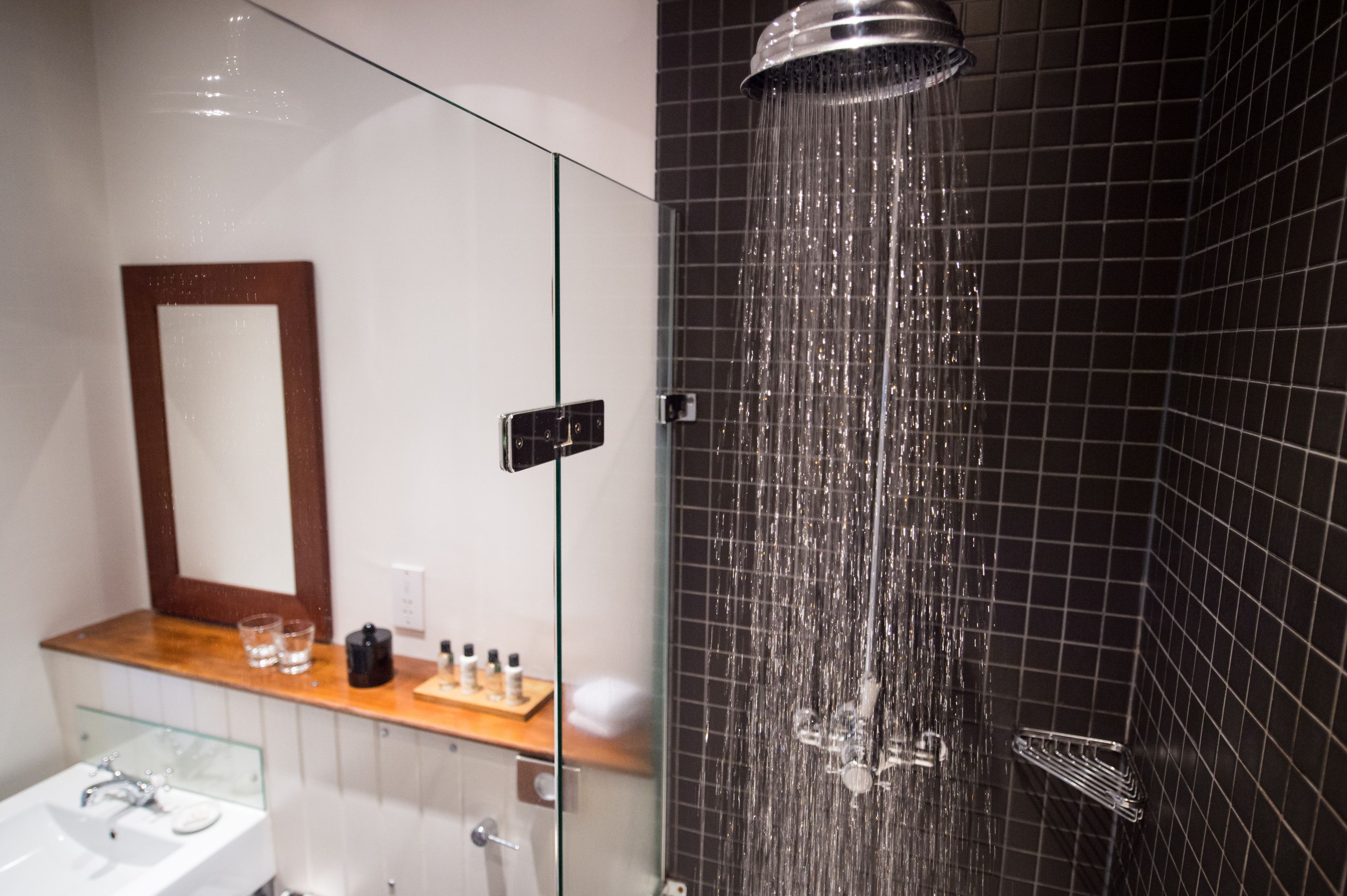 A modern bathroom with a glass shower enclosure, a wooden vanity, and a large mirror.