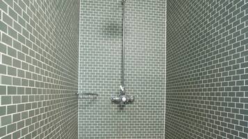 Shower area features a modern showerhead and green-tiled walls and floor.