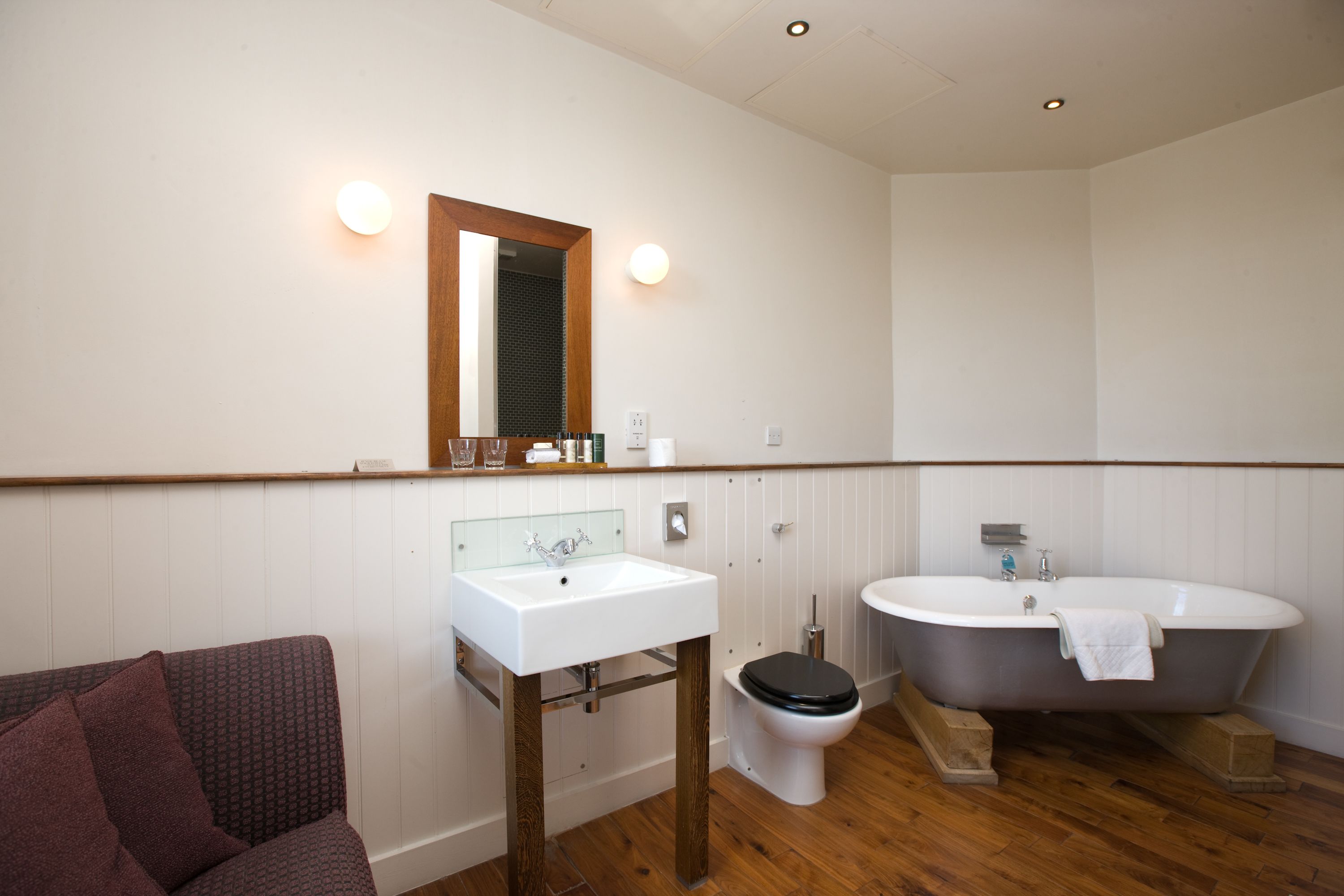 Une salle de bain avec un lavabo blanc, des toilettes et une baignoire sur pieds.