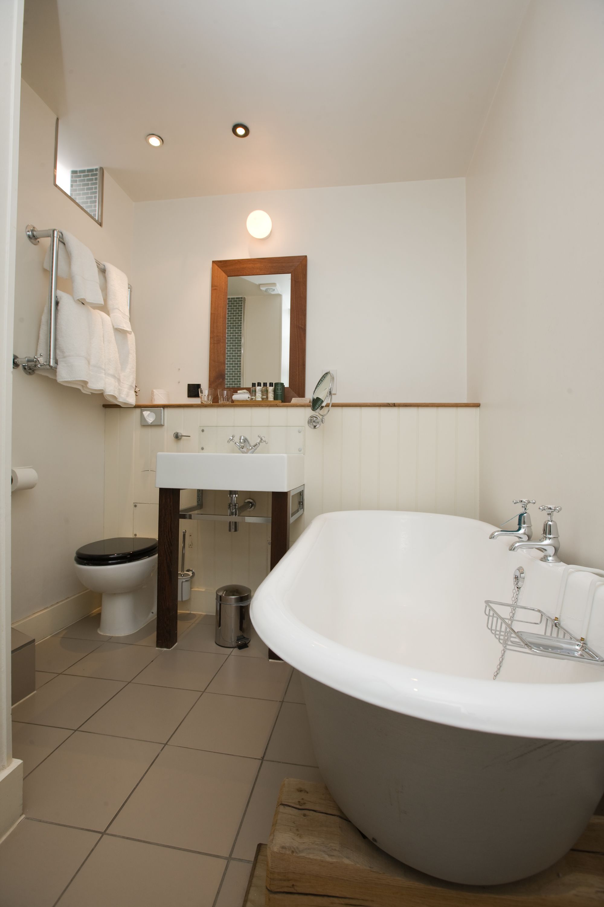 Un baño con una bañera independiente, un inodoro, un lavabo y un espejo.