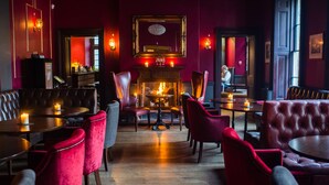 Un acogedor interior de restaurante con asientos de cuero, chimenea e iluminación cálida.