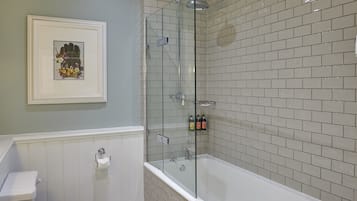 A bathroom with a glass-enclosed shower, a white bathtub, and a toilet.
